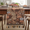 Beige jacquard table runner with long tassels and floral leaf pattern laid on a dining table.