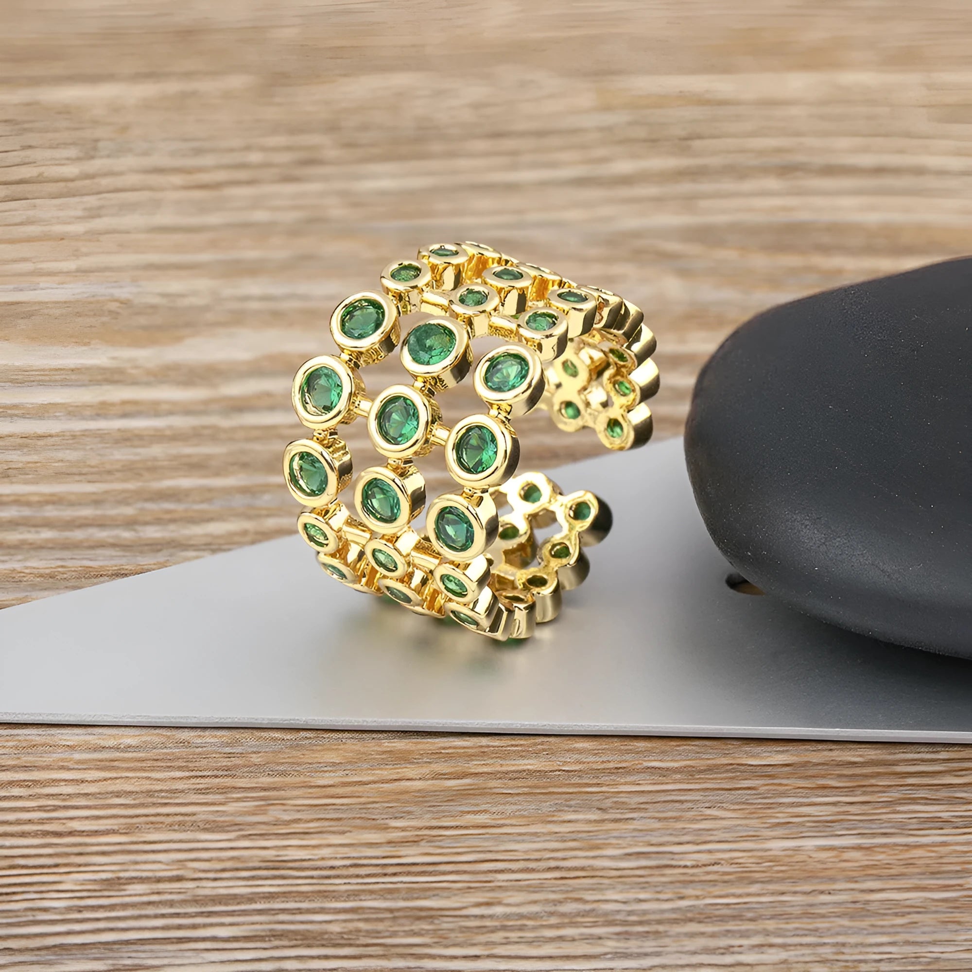 Gold-coloured wide ring with a textured three-layer exaggerated design on a plain background.
