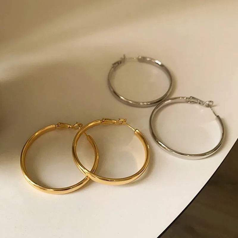 A pair of large 40mm gold metal circle hoop earrings on a white background.