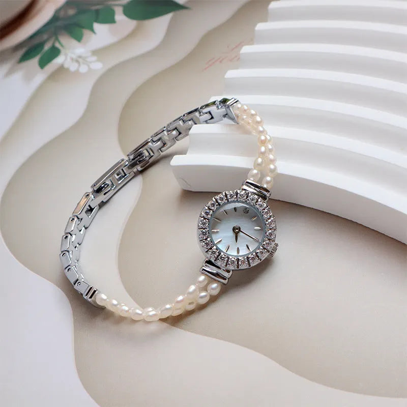 Light gold women's bracelet watch with freshwater pearls on stainless steel strap and round dial.
