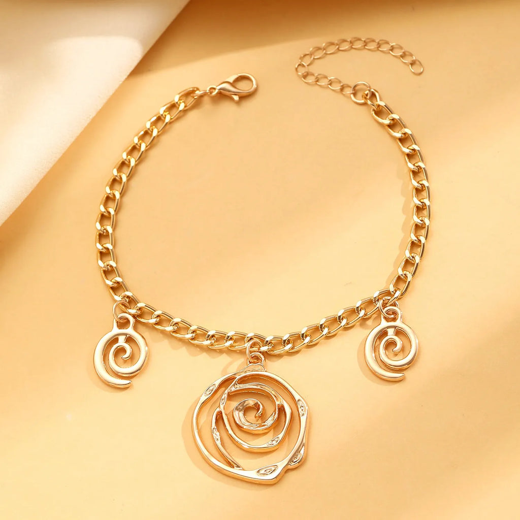 Gold spiral donut geometric jewellery set with adjustable necklace, matching bracelet, and earrings on a white background.