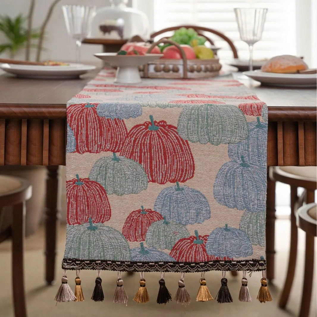 Beige jacquard table runner with long tassels and floral leaf pattern laid on a dining table.