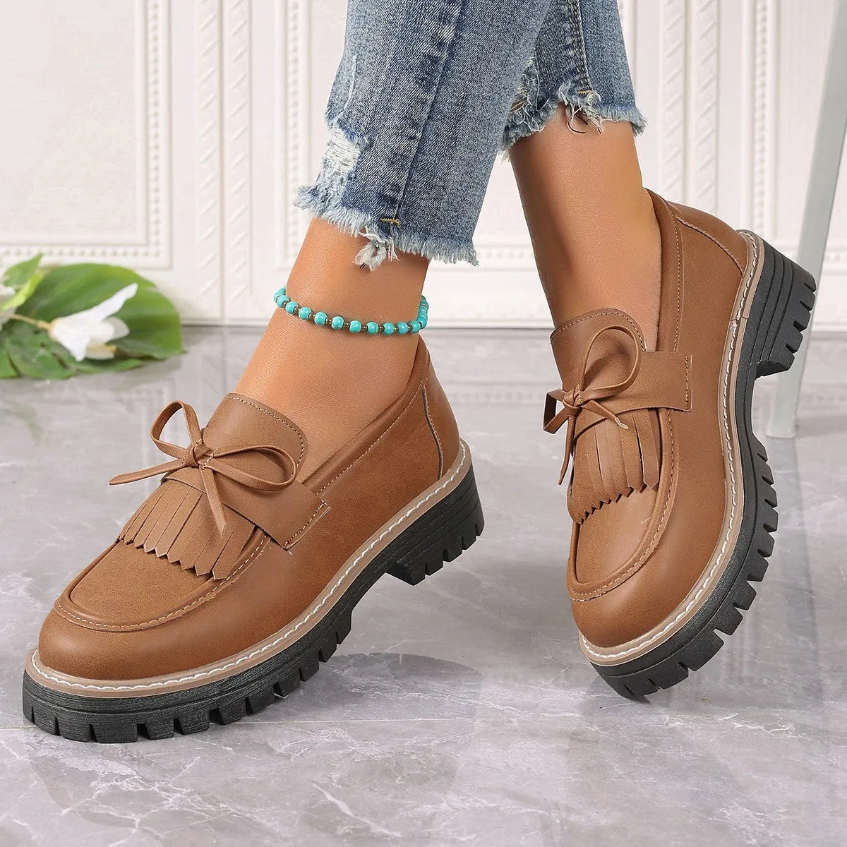 Black and brown women's loafers with a tassel bow detail and a chunky low heel.