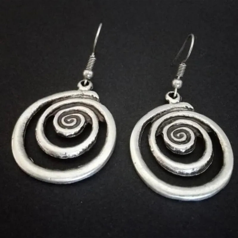 Close-up of silver-coloured geometric spiral earrings with a distressed retro finish.