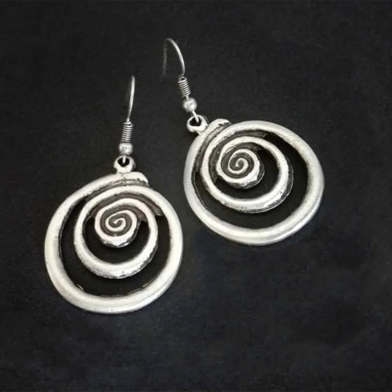 Close-up of silver-coloured geometric spiral earrings with a distressed retro finish.