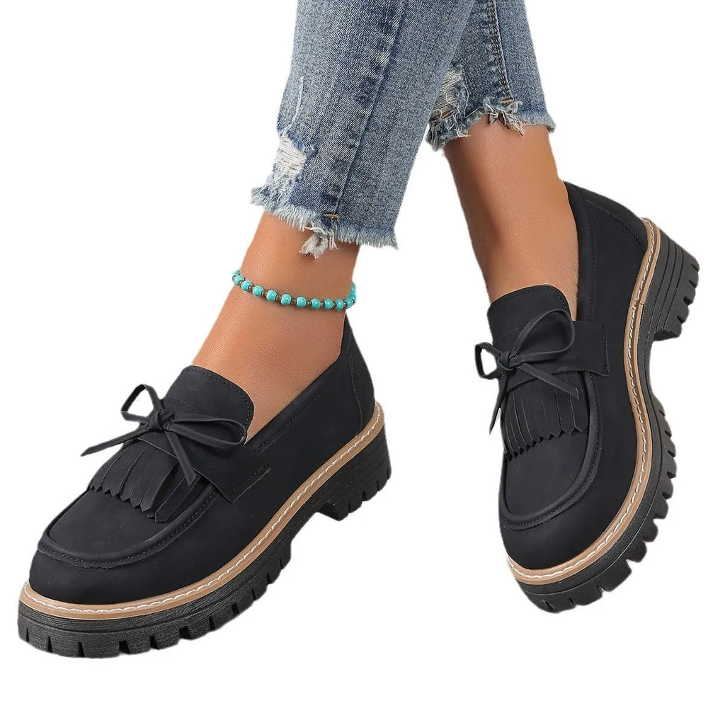 Black and brown women's loafers with a tassel bow detail and a chunky low heel.