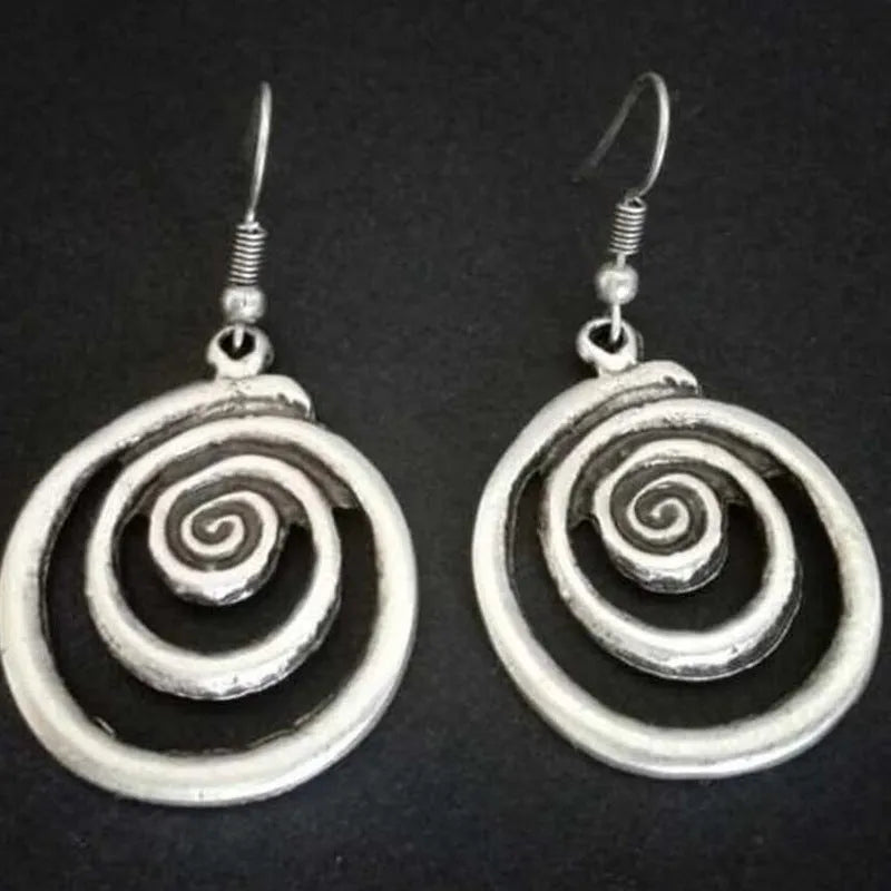 Close-up of silver-coloured geometric spiral earrings with a distressed retro finish.