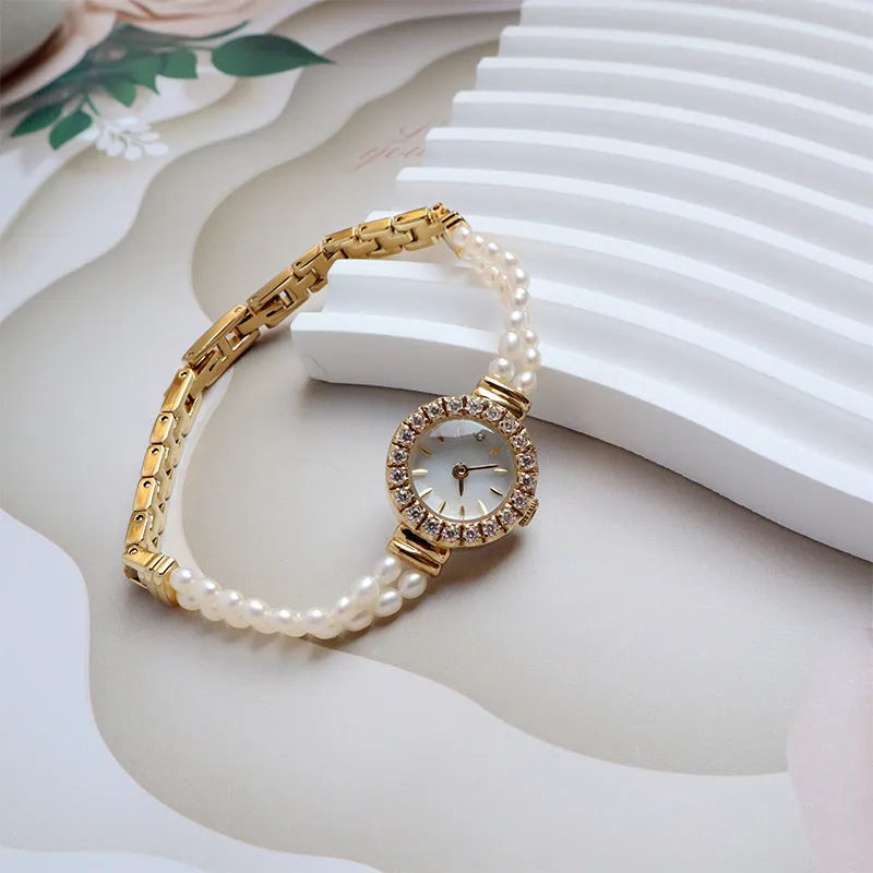 Light gold women's bracelet watch with freshwater pearls on stainless steel strap and round dial.