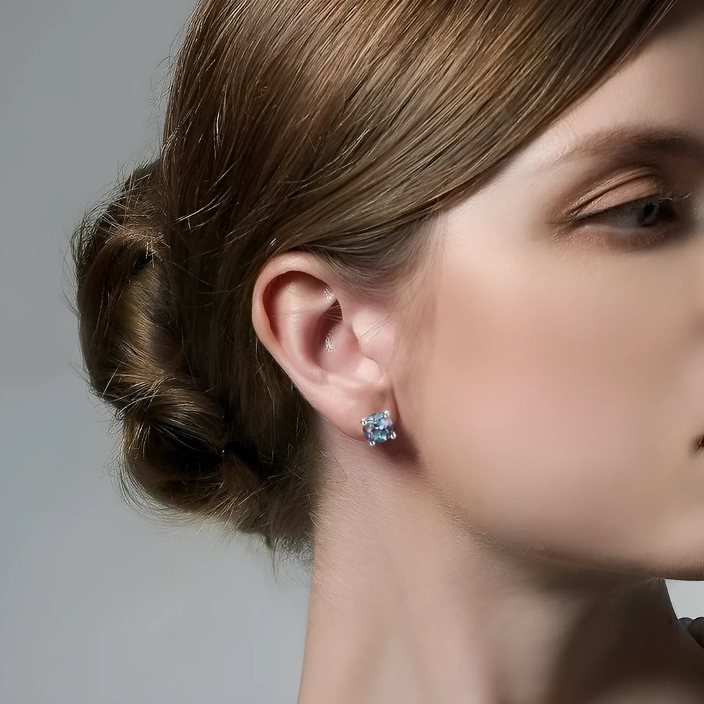 Simple geometric round ear studs in silver with a purple-green cultivate Alexandrite stone.