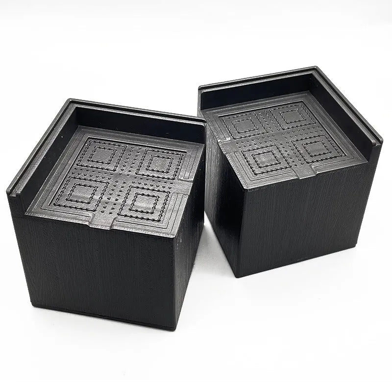 Four black plastic bed foot riser mats for furniture height increasing