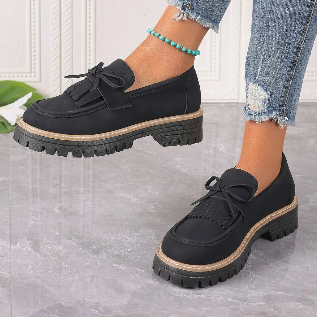 Black and brown women's loafers with a tassel bow detail and a chunky low heel.
