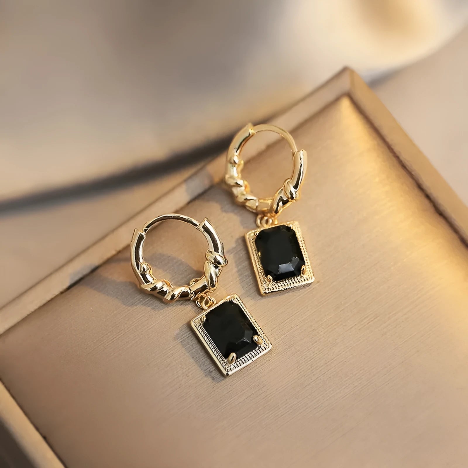 A pair of geometric black zircon earrings with a quadrilateral shape on a copper setting.