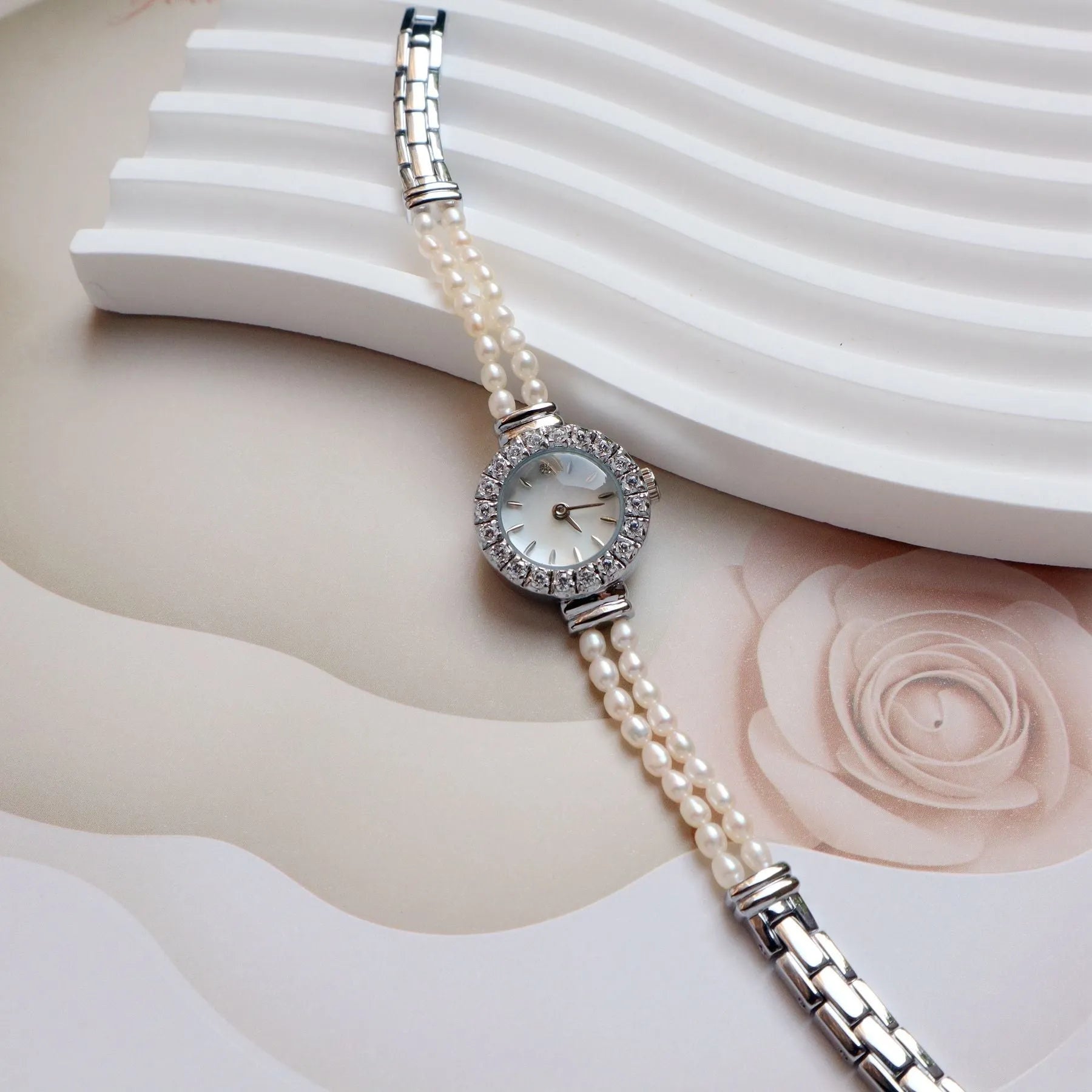 Light gold women's bracelet watch with freshwater pearls on stainless steel strap and round dial.
