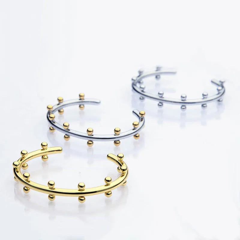 Stainless steel C-shaped bracelet with textured rivet bean beads in gold or steel colour.