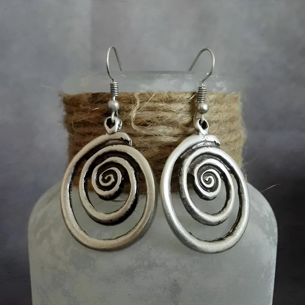 Close-up of silver-coloured geometric spiral earrings with a distressed retro finish.