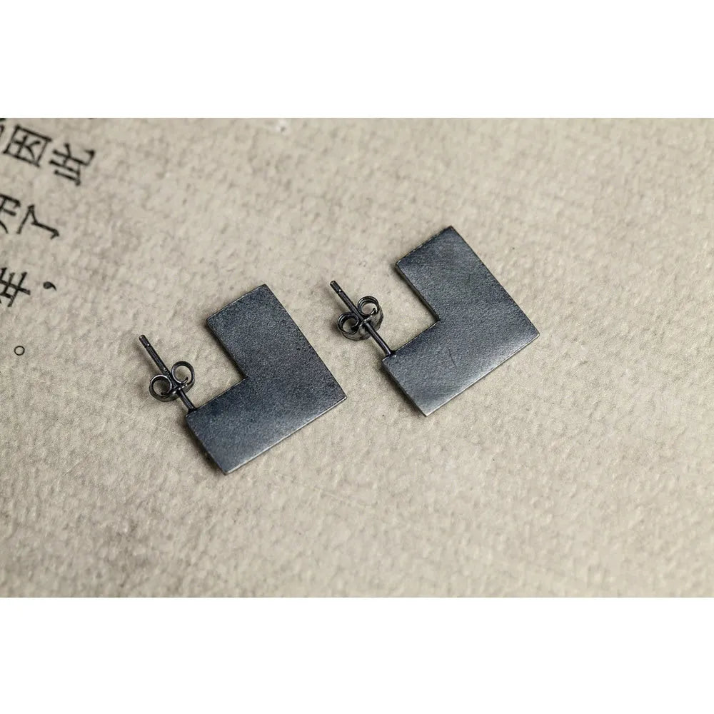 Square oxidised black sterling silver geometric earrings on a white background.