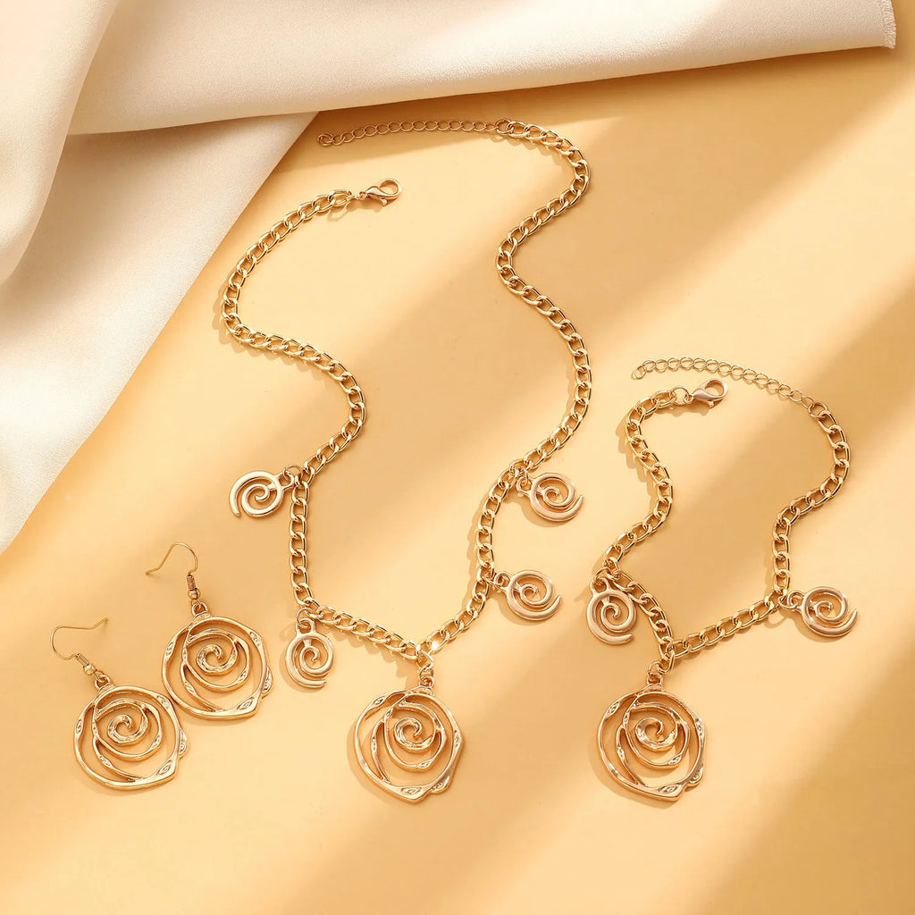 Gold spiral donut geometric jewellery set with adjustable necklace, matching bracelet, and earrings on a white background.