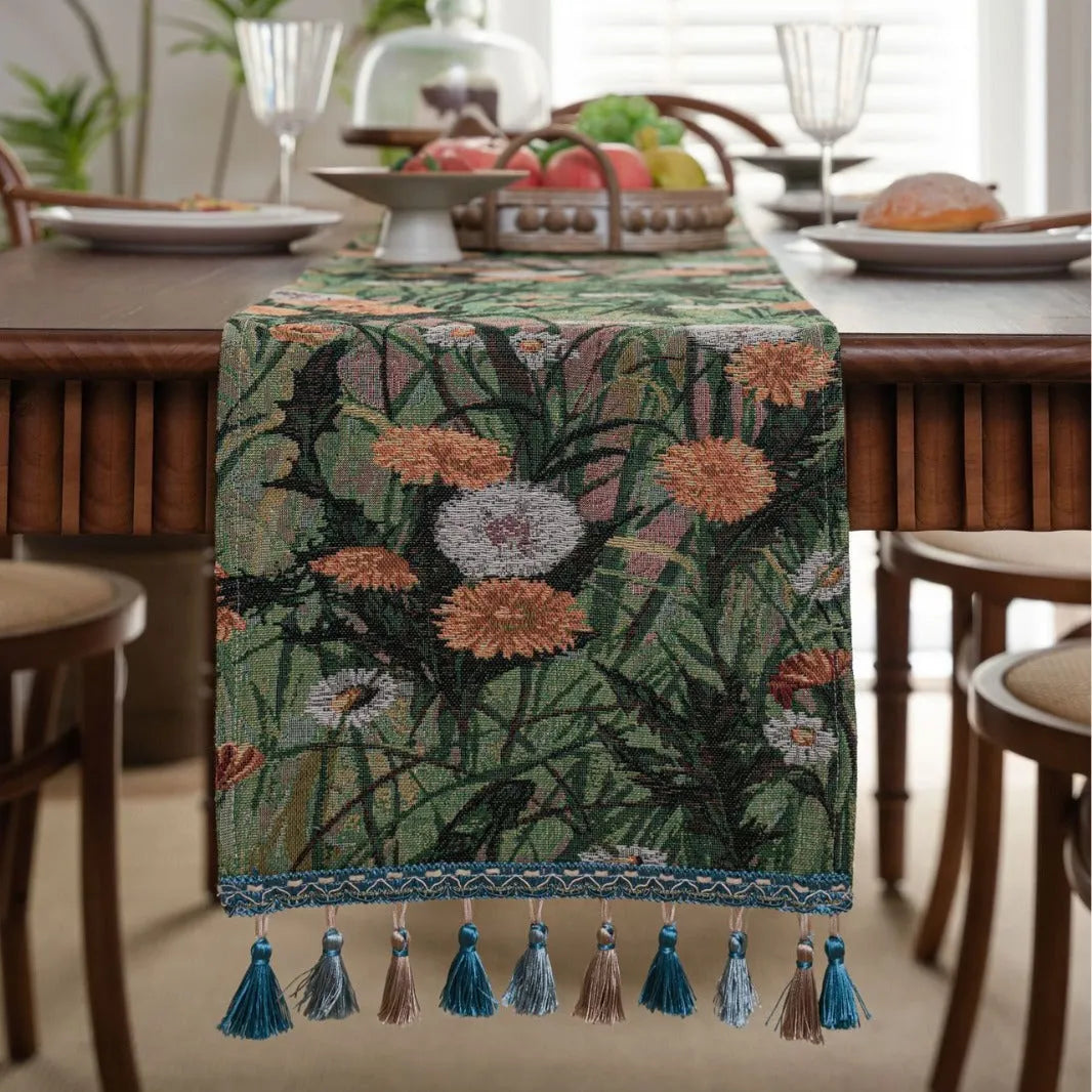 Beige jacquard table runner with long tassels and floral leaf pattern laid on a dining table.