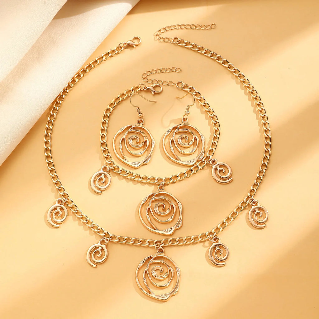 Gold spiral donut geometric jewellery set with adjustable necklace, matching bracelet, and earrings on a white background.