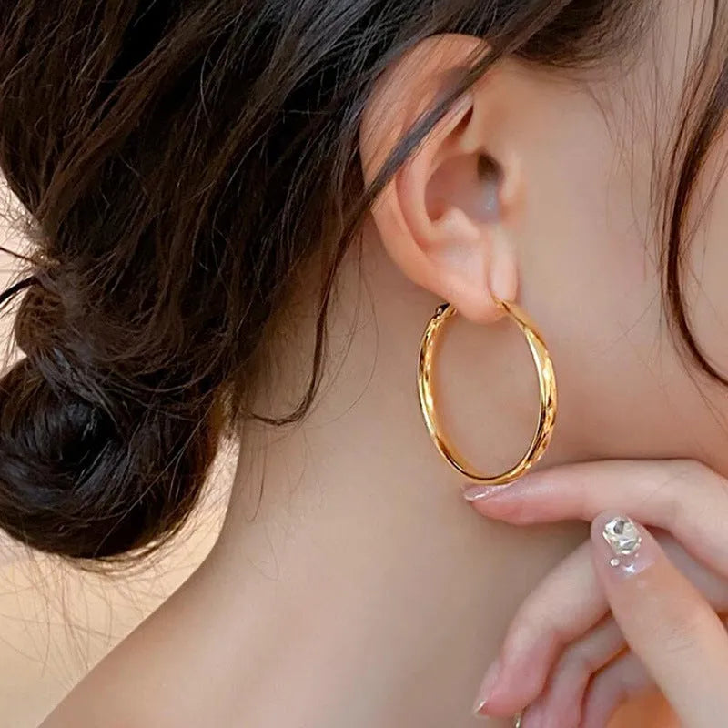 A pair of large 40mm gold metal circle hoop earrings on a white background.