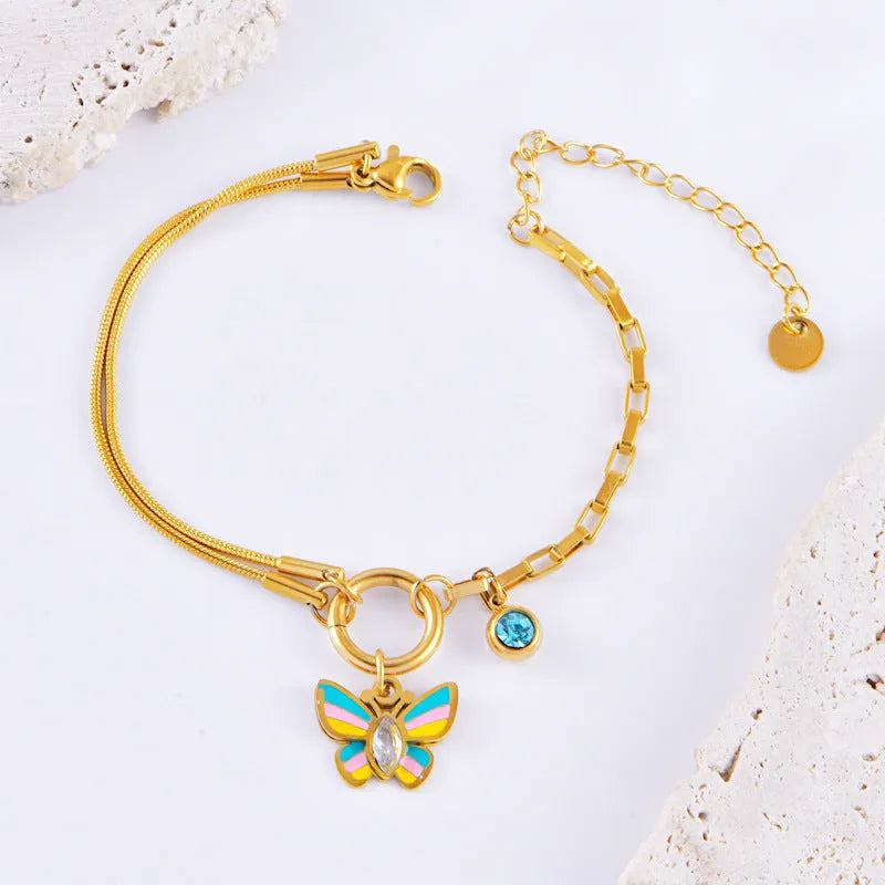 Gold titanium steel butterfly necklace and matching bracelet set on a dark background.