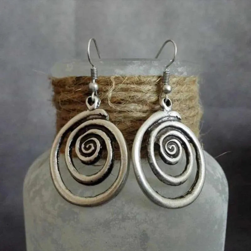Close-up of silver-coloured geometric spiral earrings with a distressed retro finish.