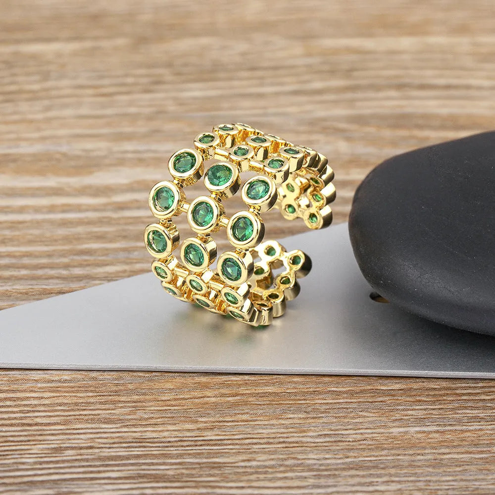 Gold-coloured wide ring with a textured three-layer exaggerated design on a plain background.