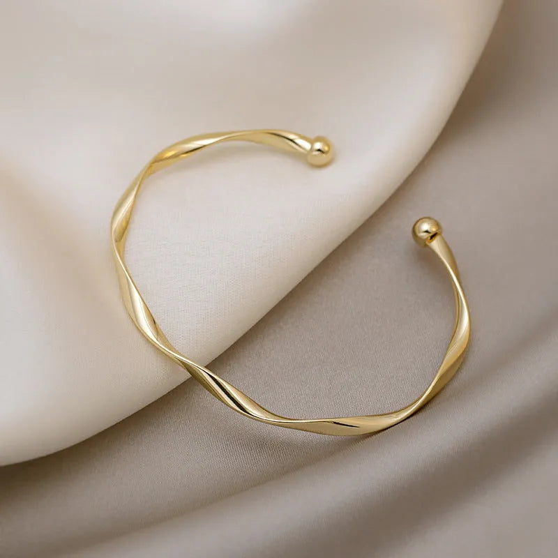 Gold alloy geometric twist bracelet with 6.2 cm inner ring diameter on white background
