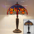 Tiffany style stone table lamp with blue dragonfly design on a bedside table.