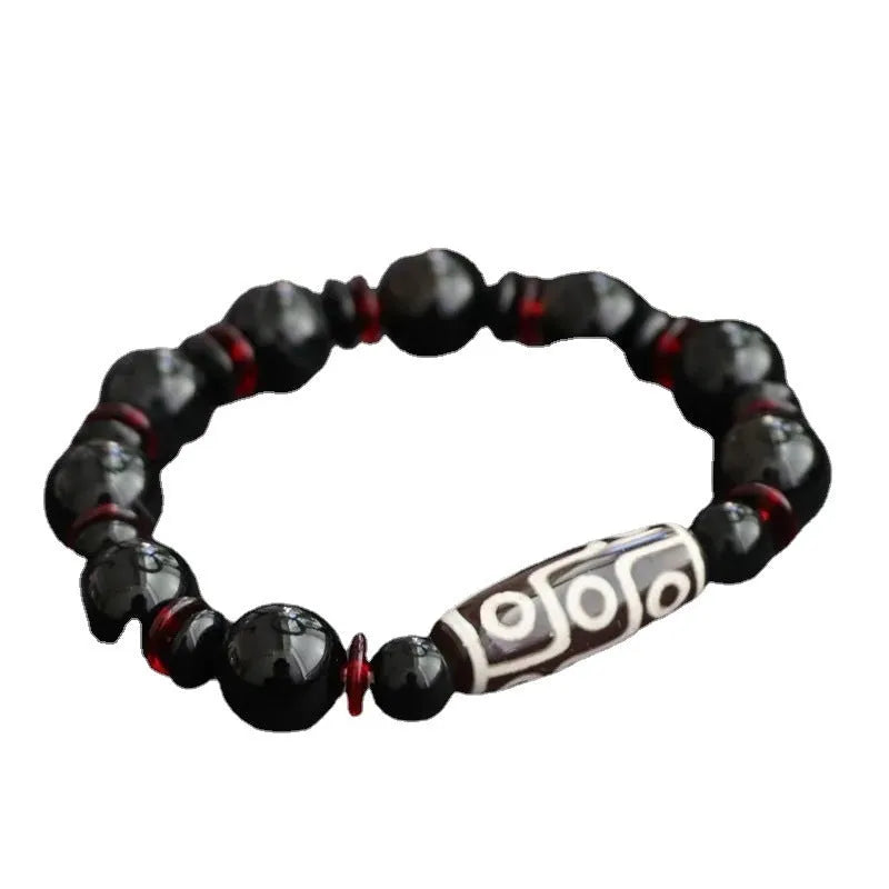 Close-up of a hand-woven black agate dzi bead bracelet with 11mm geometric beads on a wrist.