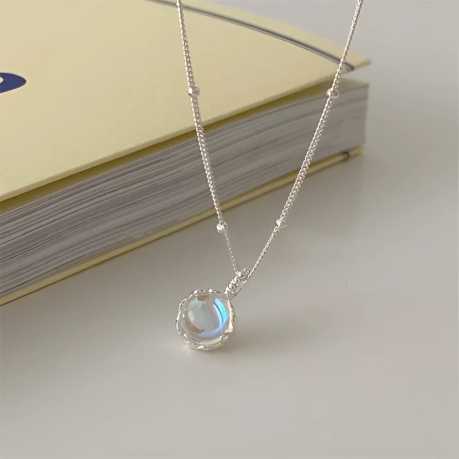 Silver geometric ornamental stone pendant on a curb chain necklace for women.