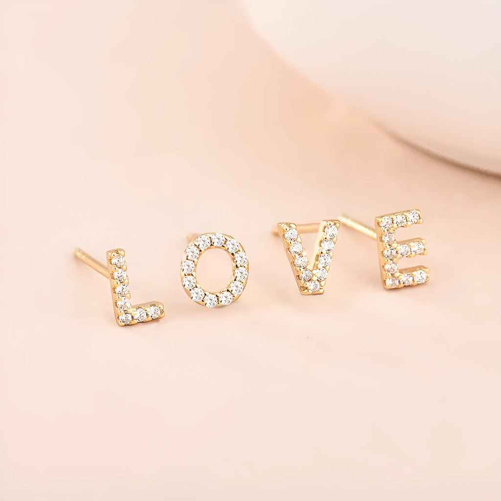 A pair of brass stud earrings featuring a single gold-plated English alphabet letter.
