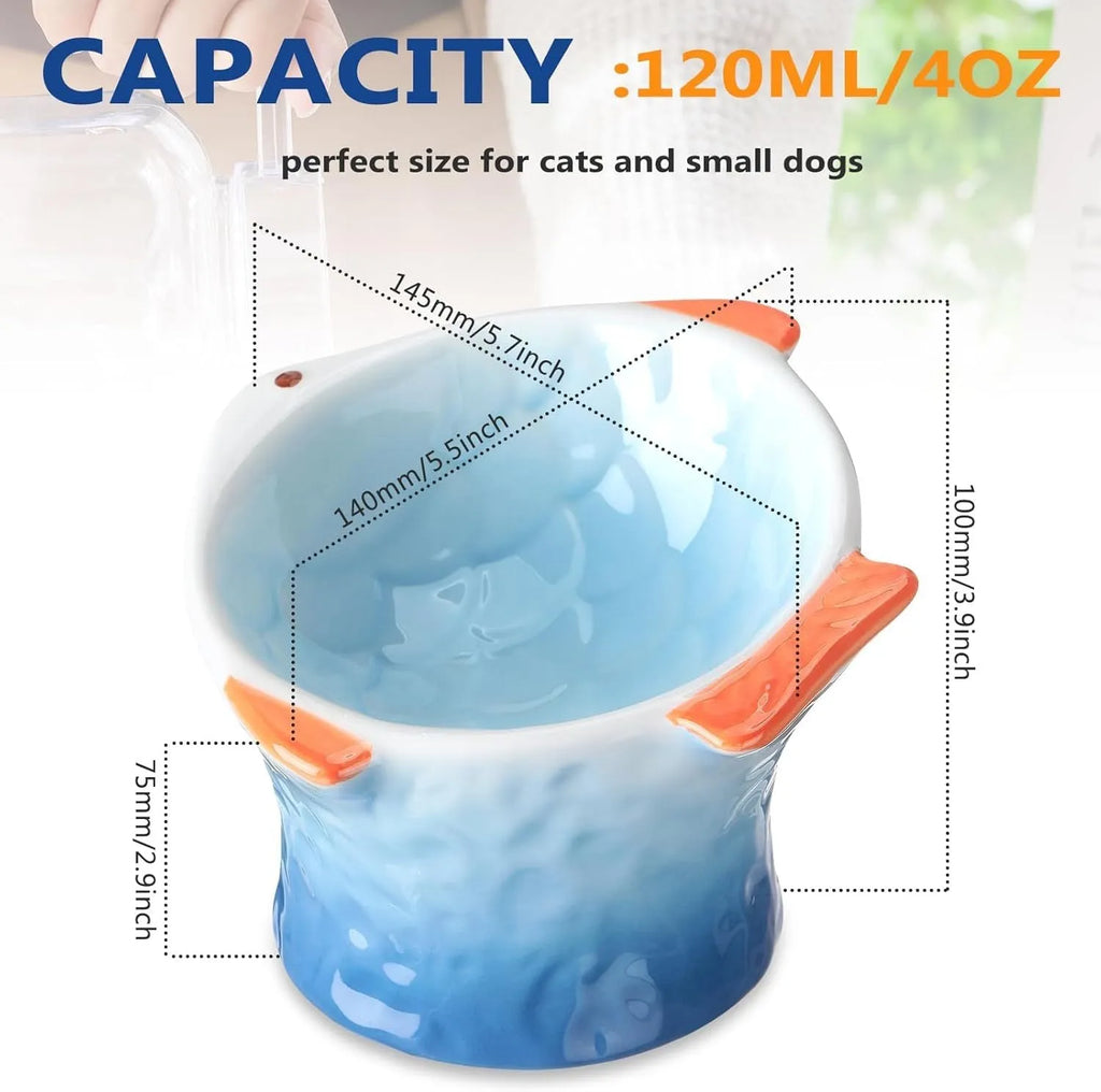 Blue fish-shaped ceramic cat bowl with tilted angle and elevated base on a table.
