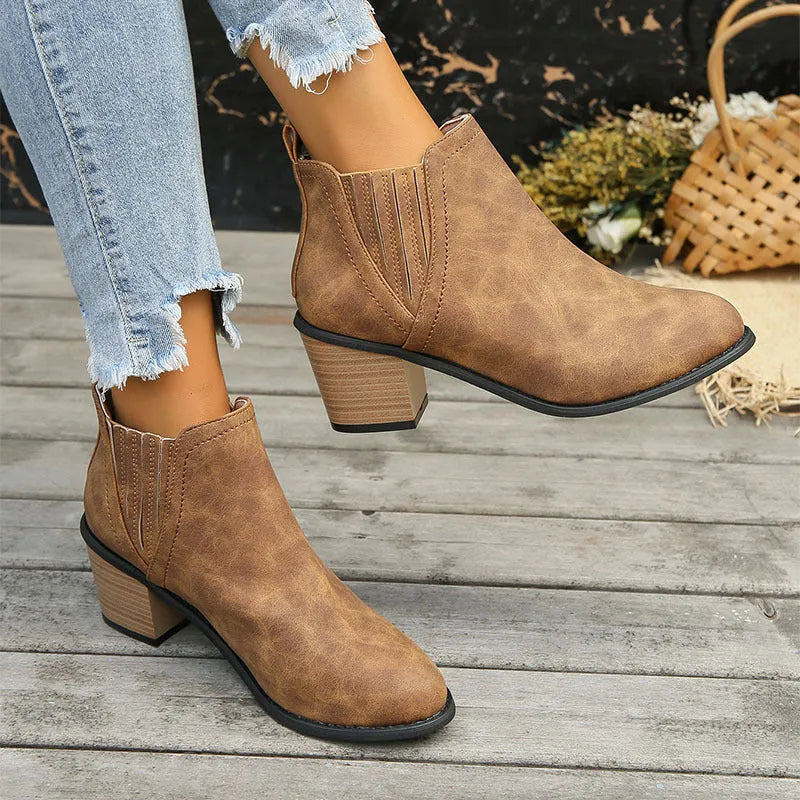 Black women's slip-on ankle boots with a pointed toe and a thick, low square heel on a rubber sole.