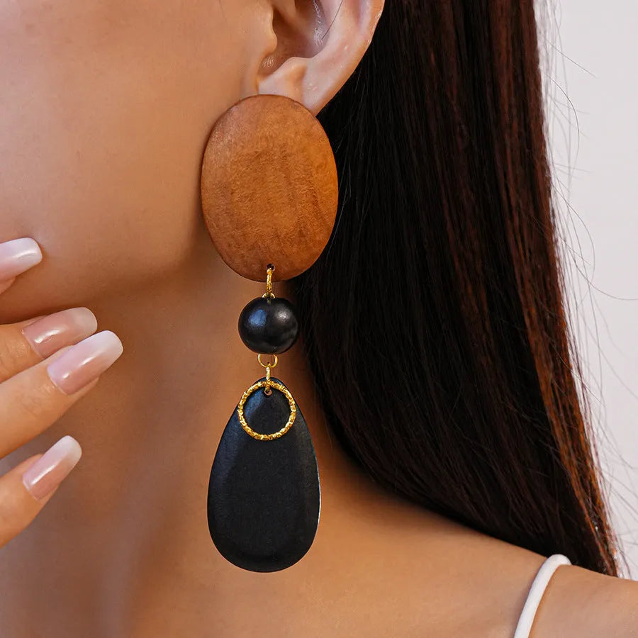 A pair of handmade brown and black wooden elliptical earrings in a retro style.