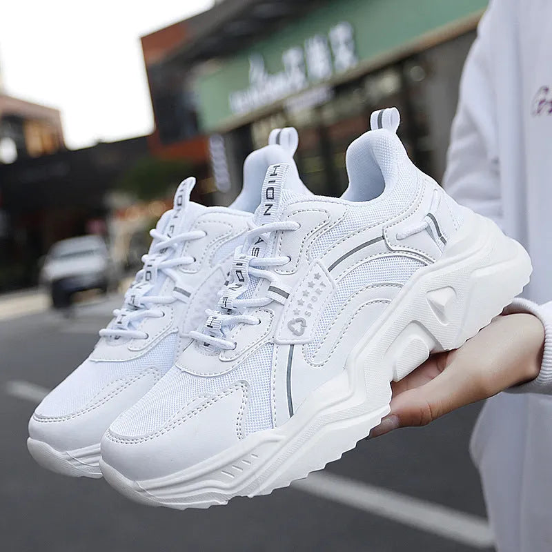 White women's casual mesh sports shoe with thick sole, buckle detail, and round toe.
