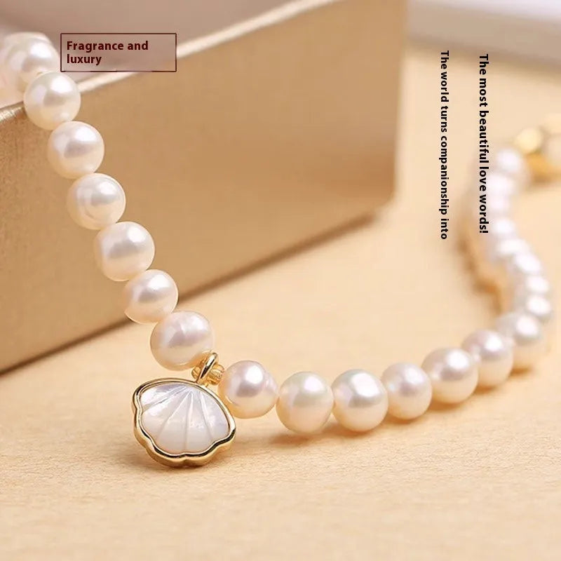 Women's freshwater pearl bracelet with a gold-toned fan charm on a 16cm elastic string.