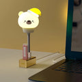 USB portable cartoon animal LED night light with remote control on a bedside table
