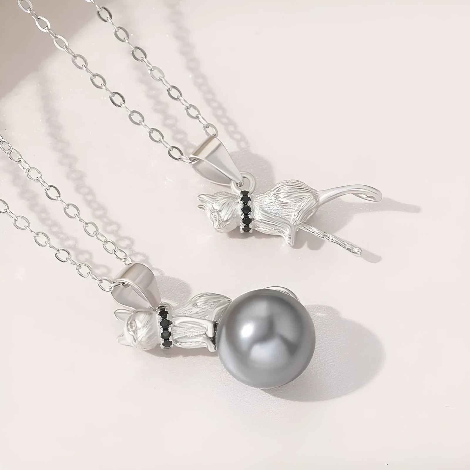 Close-up of a sterling silver cat pendant necklace on a clavicle-length chain, showing the electroplated finish.