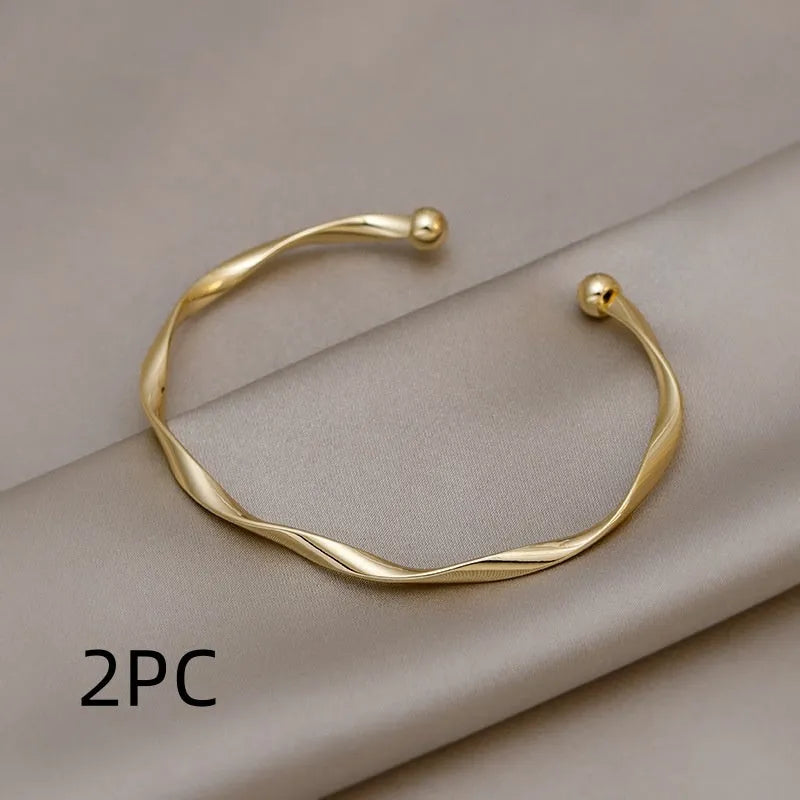 Gold alloy geometric twist bracelet with 6.2 cm inner ring diameter on white background