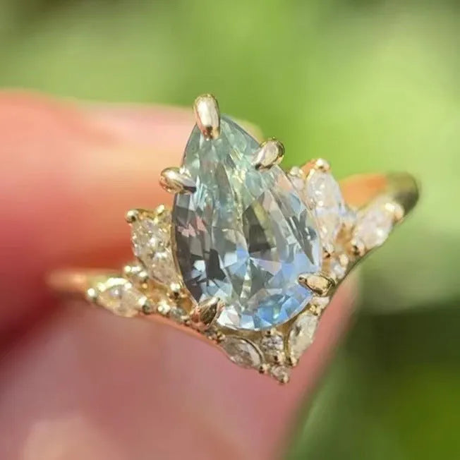 Gold alloy ring with blue crystal diamond inlay and floral design on white background