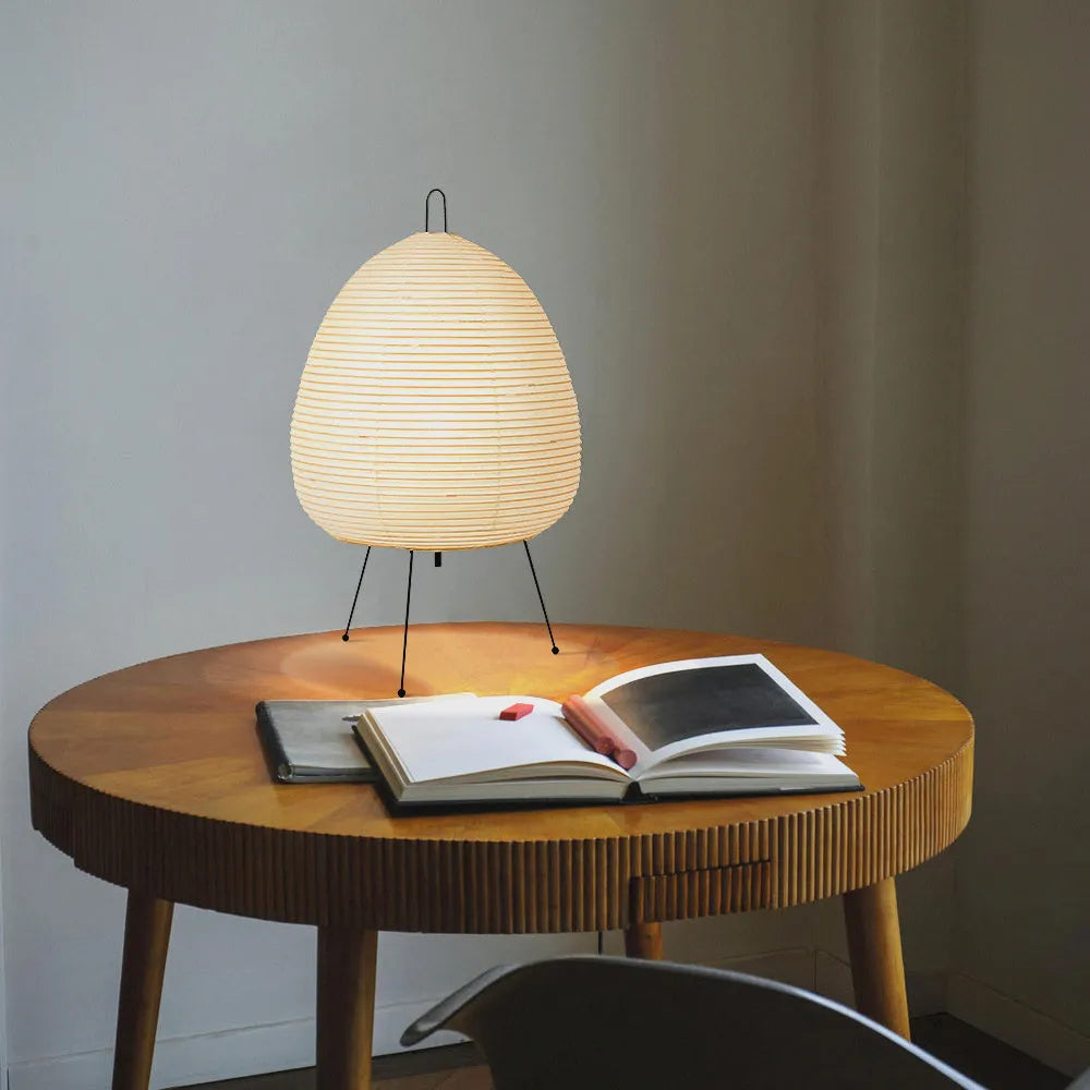 Japanese style table lamp with handmade paper shade and aluminium base on a wooden surface.