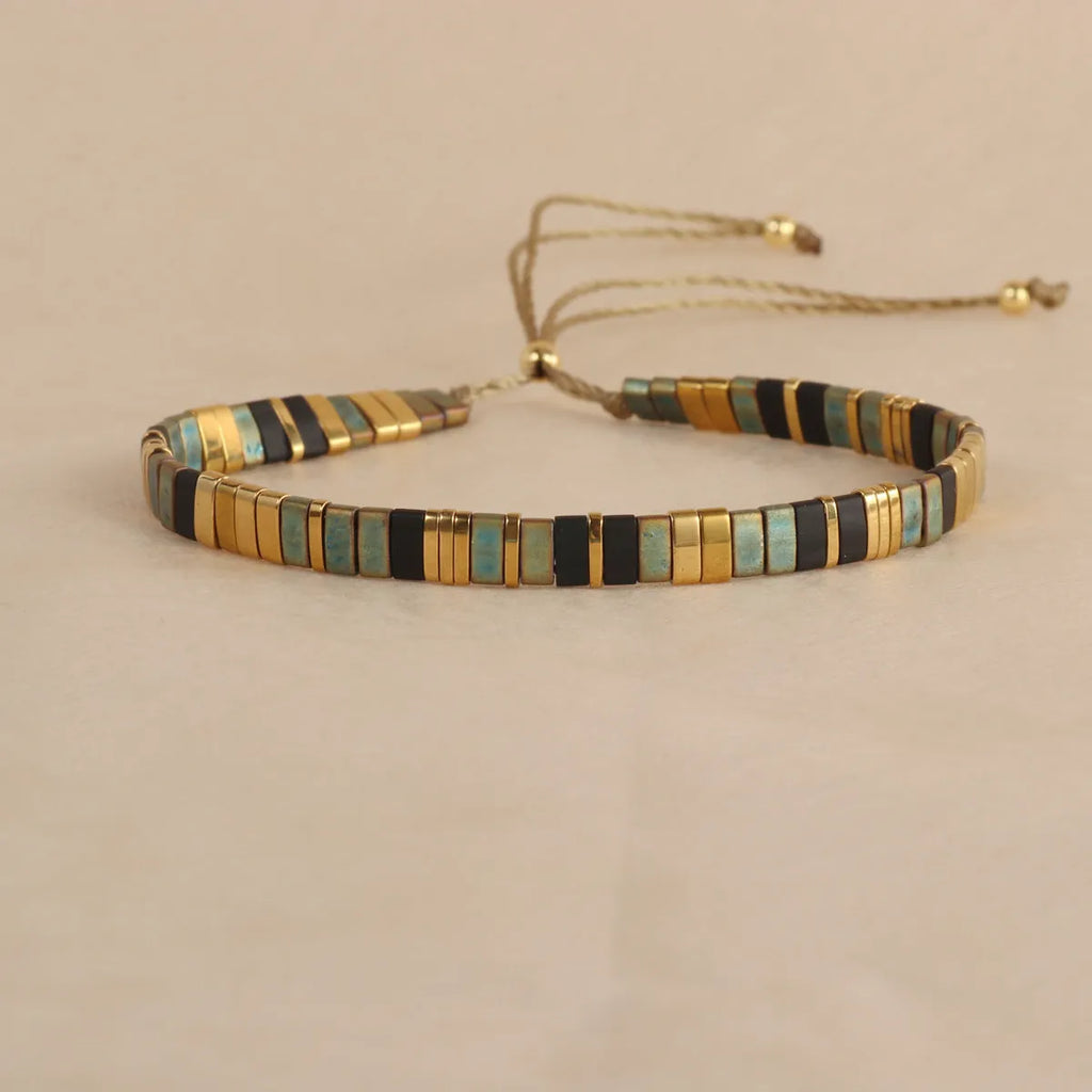 Adjustable geometric beaded bracelet with pull beads in milky white, black, green, blue or red.
