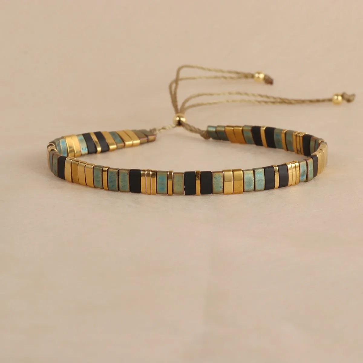 Adjustable geometric beaded bracelet with pull beads in milky white, black, green, blue or red.