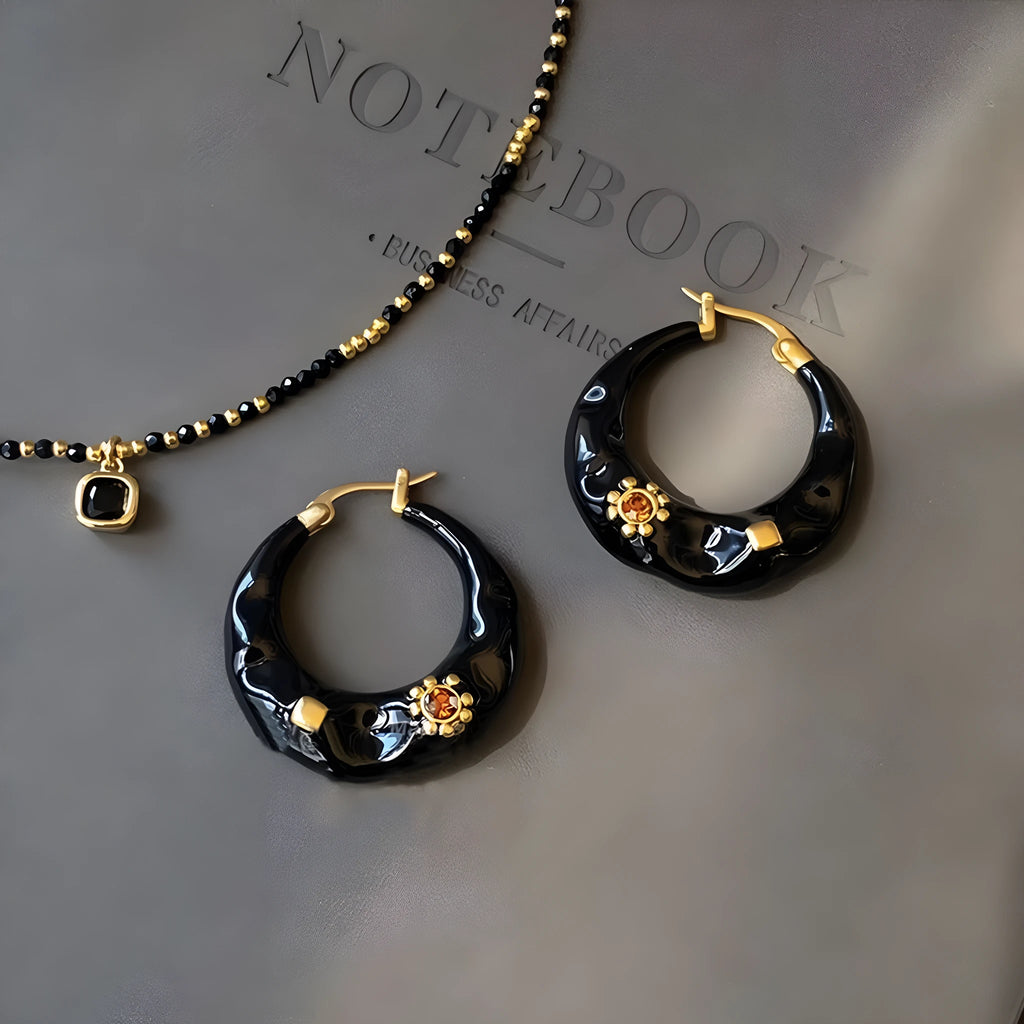A pair of retro alloy ear studs with a dripping oil finish and black rhinestone detail.