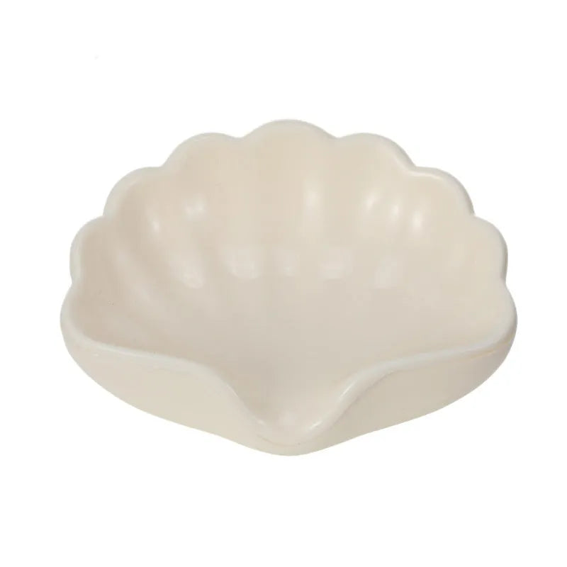 White shell-shaped plastic soap dish for bathroom use on a countertop.