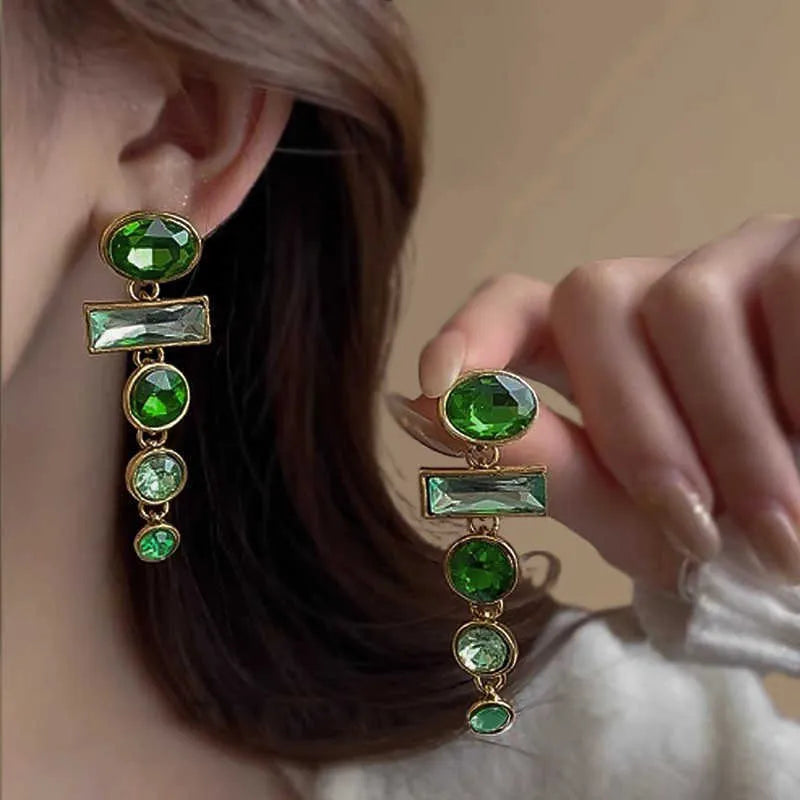 A pair of green gradient alloy earrings with geometric shapes, inlaid zircon stones, and decorative tassels.