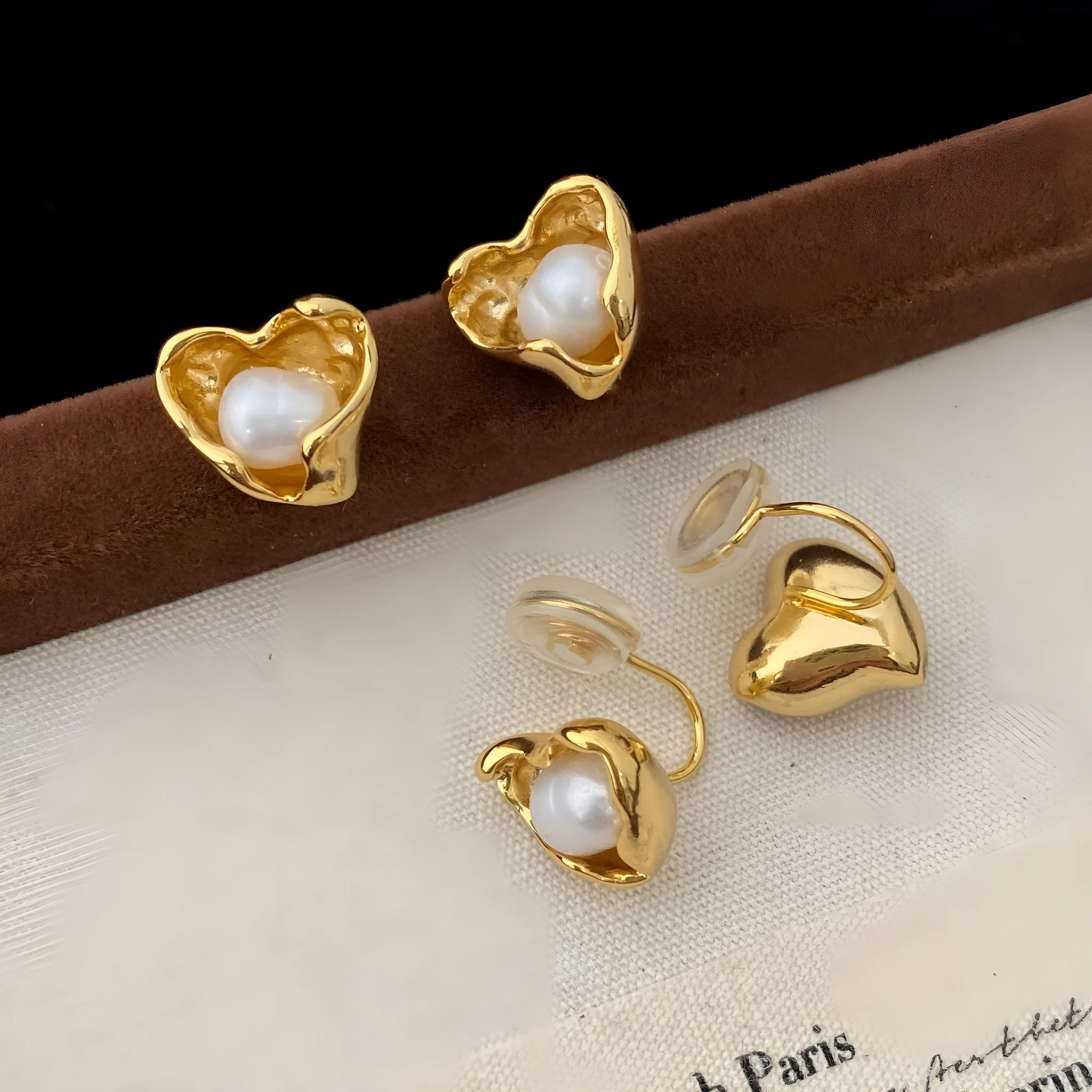 Pair of copper heart shaped irregular pearl earrings with electroplating finish on white background