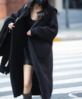 Long grey knitted hooded trench coat worn open as a cardigan.