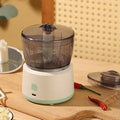 Mini electric meat grinder with transparent processing cup and stainless steel blades in white or light green